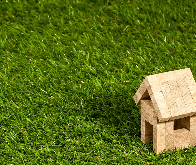 A house made of blocks sits on grass