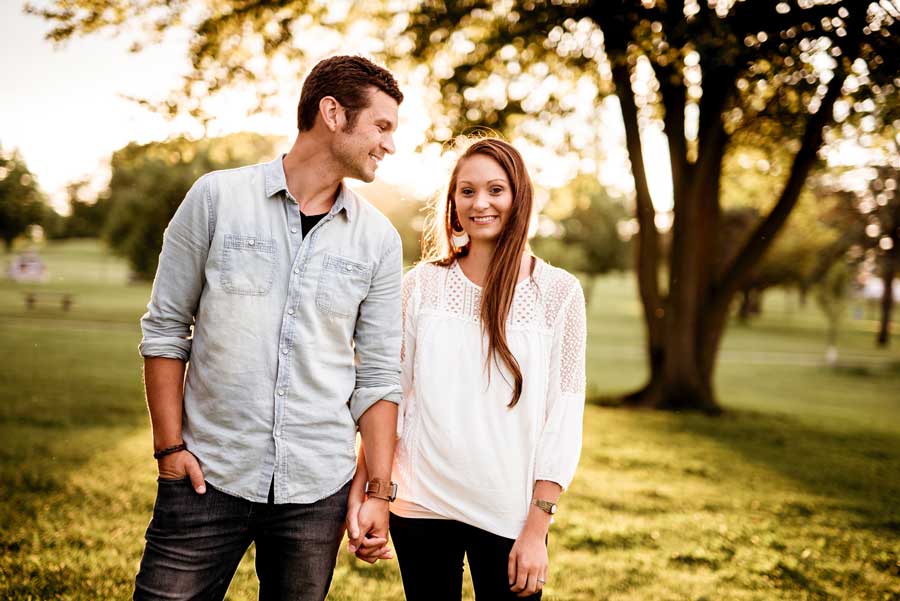 Couple standing smiling in large yard.