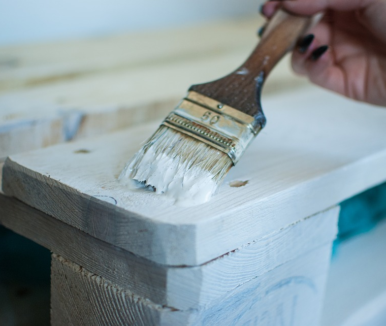 Close-up of someone painting wood white