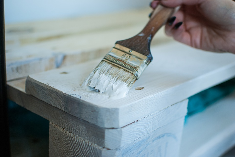 Close-up of someone painting wood white