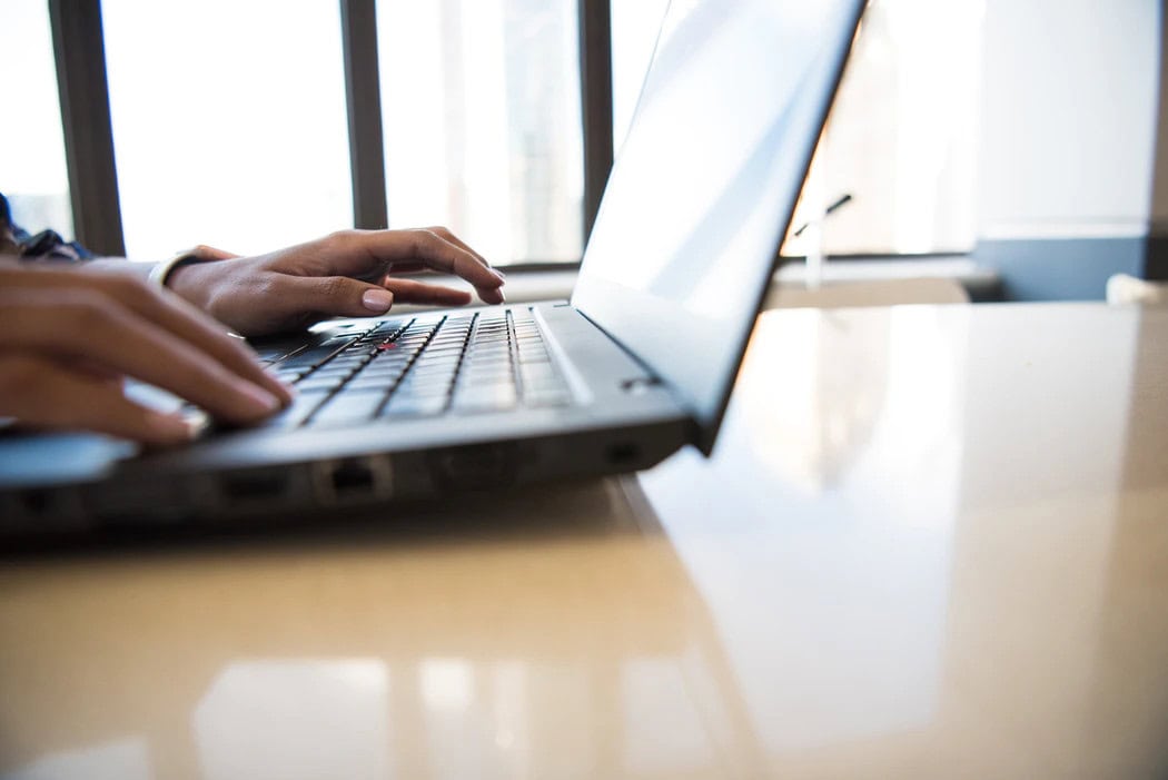 Close-up of hands typing on a laptop