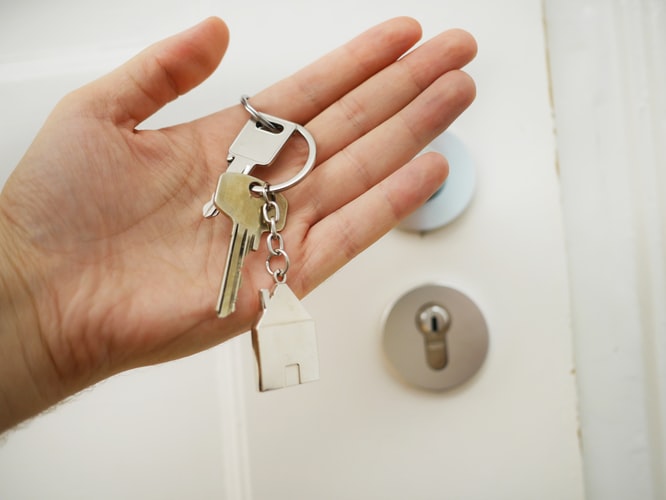 person's hand holding keys to their new house with a house-shaped keychain