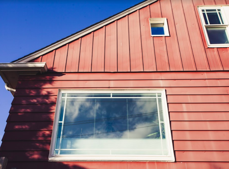 photo of a window in a house reflecting blue sky and puffy white clouds
