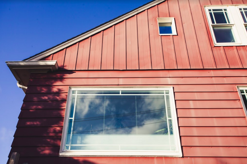 photo of a window in a house reflecting blue sky and puffy white clouds